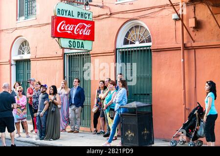 New Orleans, USA - 23. April 2018: Retro-Vintage-Zeichen für Coca-Cola Soda und königliche Apotheke auf der Straße in Louisiana Stadt und vielen Menschen Stockfoto