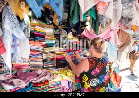 Firenze, Italien - 30. August 2018: Frau, die viele Schals kauft, farbenfrohe Farben, die auf dem Einkaufsmarkt in Florenz, Toskana zu sehen sind Stockfoto