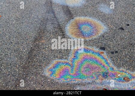 Bunte Gasflecken auf einer Asphaltstraße. Reifenspuren sichtbar. Stockfoto