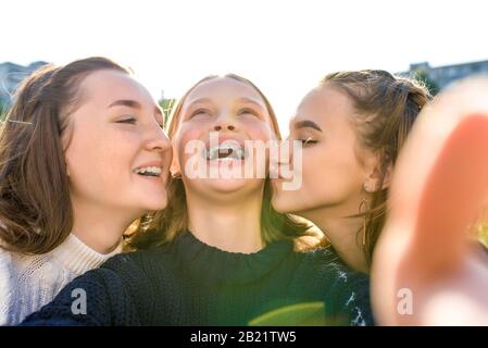 3 Mädchen im Teenager-Alter, die Videofoto auf dem Telefon aufzeichnen. Im Sommer in der Stadt. Emotionen der Überraschung, des Glücks, des Lachens, der Freude, des Spaßes, des fröhlichen Lächelns. Selfie Stockfoto