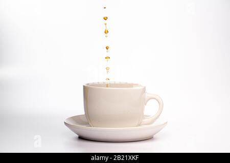 Kaffee wird in eine weiße Tasse mit Untertasse gegeben Stockfoto