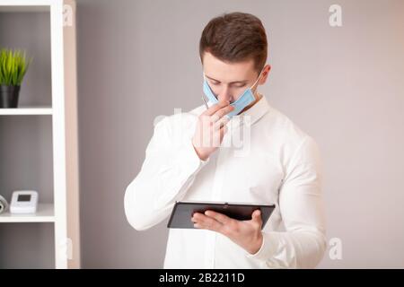 Mann in Schutzmaske Arbeiten am Tablet im Büro Stockfoto