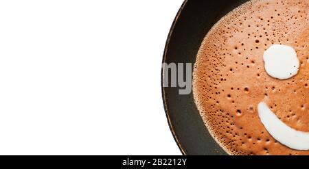 Banner mit Leerzeichen für Text. Ein Pfannkuchen aus flüssigem Schokoladen-Teig mit Blasen wird in einer schwarzen Pfanne mit Tropfen Fett und Öl auf einem Kanal gebraten Stockfoto