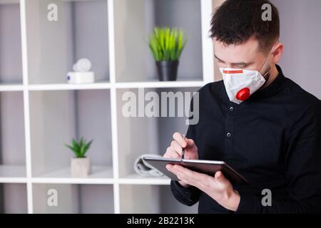 Mann in Schutzmaske Arbeiten am Tablet im Büro Stockfoto