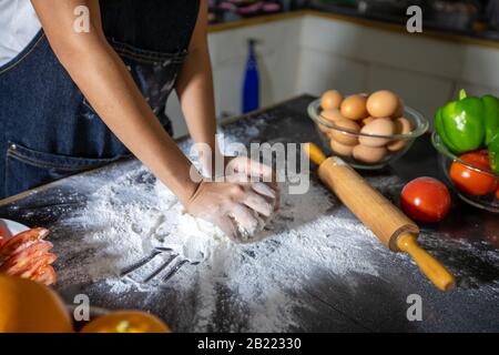 Asiatische Frauen Vorbereitung einer Pizza, kneten Sie den Teig und Zutaten auf dem Küchentisch Stockfoto