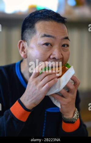 Ein japanischer Mann genießt einen Burger in einem Diner in Tokio Stockfoto
