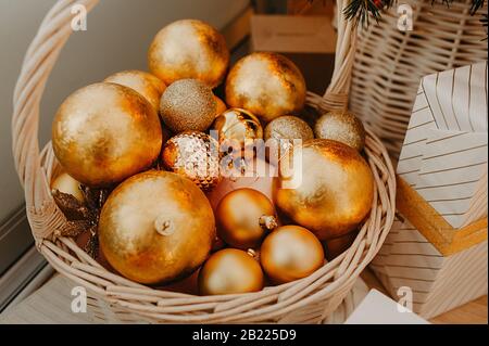 Riesiger Korbkorb, der oben mit goldenen Kugeln gefüllt ist, um einen Weihnachtsbaum oder eine Wohnung zu schmücken Stockfoto