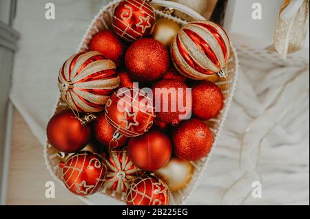 Riesiger Korbkorb, der oben mit roten und goldenen Kugeln gefüllt ist, um einen Weihnachtsbaum oder eine Wohnung zu schmücken Stockfoto