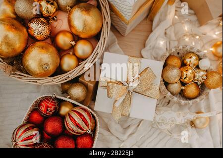 Riesiger Korbkorb, der oben mit roten und goldenen Kugeln gefüllt ist, um einen Weihnachtsbaum oder eine Wohnung zu schmücken Stockfoto