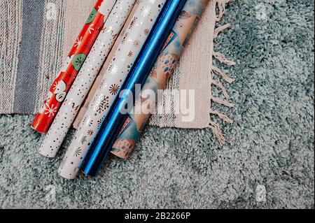 Viele bunte Wickelpapierrollen für Geburtstagsgeschenke oder eine Feier auf einem hochstapeligen blauen Teppich Stockfoto