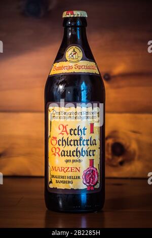 Bamberg - 23. Februar 2020: Eine Flasche Bamberg Rauchtes Bier der berühmten Schlenkerla-Brauerei in Bamberg, Bayern, Deutschland auf einem Holzbackgr Stockfoto