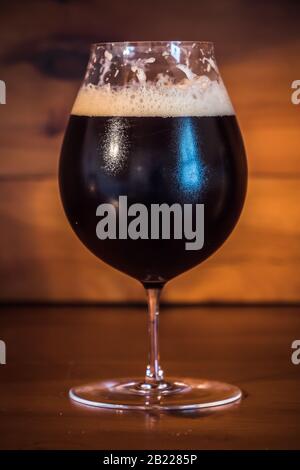 Dunkles Bier oder Ale wie Bamberger Smokebeer in einem Tulpenglas auf Holzhintergrund Stockfoto