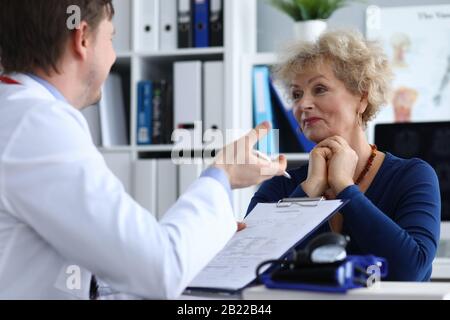 Ein männlicher Arzt fragt eine ältere Dame nach der Gesundheit Stockfoto