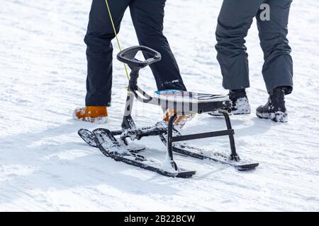 Rückansicht des Kindes beim ziehen des Schlittens und beim laufen auf einer verschneiten Piste, während Sie Zeit im Skigebiet verbringen Stockfoto