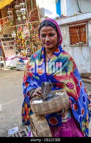 Dame mit einer Kobra im Korb auf den Straßen von Pushkar, Rajasthan, Indien Stockfoto