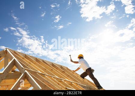 Dachdecker-Bauarbeiter arbeiten auf Dachtrusseln auf Baustelle mit blauem Himmel und Sonnenschein Stockfoto