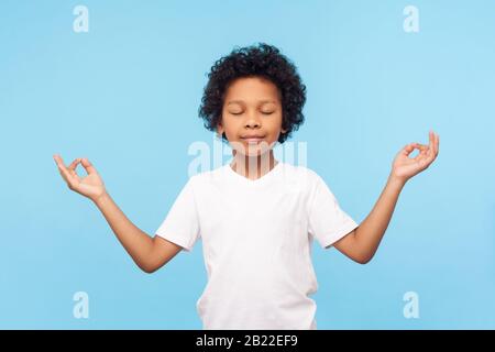 Portrait eines friedlichen, niedlichen kleinen Jungen, der mit Mudra-Geste die Finger hält und mit geschlossenen Augen meditiert, sich ruhig positiv und entspannt fühlt, Yoga-Praxis Stockfoto