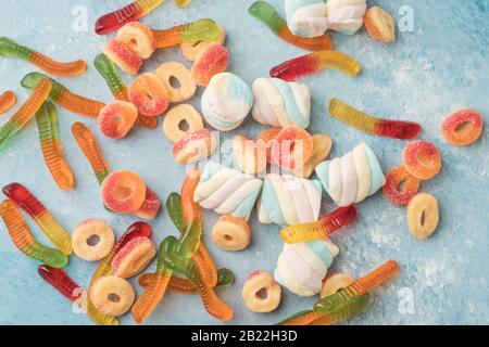 Eine Auswahl an bunten Gelee Süßigkeiten und sumpfigen Süßigkeiten auf blauem Hintergrund Stockfoto