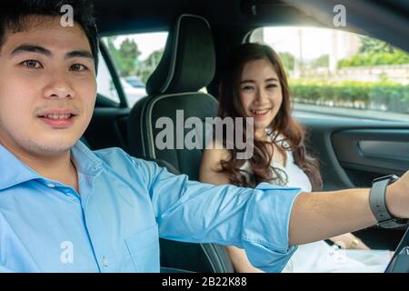 Asiatische Paare fahren in einem Auto zur Probefahrt, bevor sie neues Auto kaufen, Stockfoto