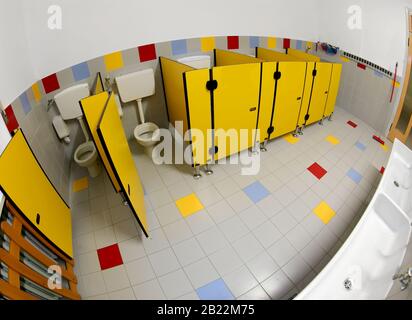 Viele gelbe Türen eines breiten Badezimmertabors eines Kindergartens ohne Menschen mit Fischaugenobjektiv Stockfoto