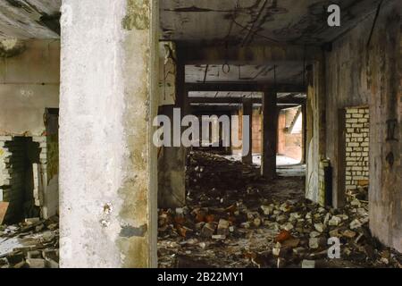 Das Innere eines zerstörten Gebäudes mit einem Haufen Betonschutt und Backsteinen mit einem grauen Balken im Vordergrund. Kopierbereich. Stockfoto