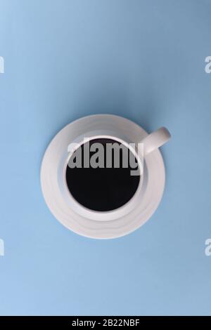 Draufsicht über Kaffee in Tasse mit Schaum auf blauem Hintergrund, schwarzer Kaffee mit Schaum auf dem Oberteil Stockfoto