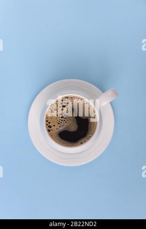 Draufsicht über Kaffee in Tasse mit Schaum auf blauem Hintergrund, schwarzer Kaffee mit Schaum auf dem Oberteil Stockfoto