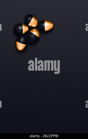 Fünf schwarze und goldene Ostereier auf schwarzem Hintergrund, vertikales Bild. Flaches Layout, Draufsicht, Kopierbereich. Stockfoto