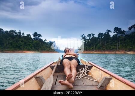 Junger Mann, der auf dem schwimmenden Boot schläft. Stockfoto