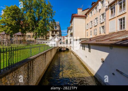 Ein Kanal am Jardin de l'Evêché mit einem Spielplatz in der Nähe von L'église Notre Dame de Liesse gegenüber der Rue Royale Brücke, Annecy, Frankreich im September. Stockfoto