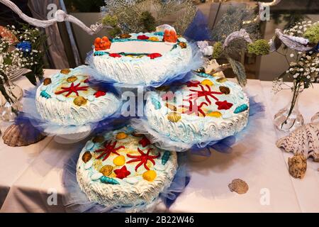 Die Schönheit der Kindheit mit einer maritimen farbigen Party mit Kuchen, die in weicher Creme und mehrfarbigen Meeresalgen in Tierform überzogen sind. Stockfoto