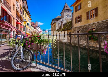 Die Rückseite des Palais de l'Ile mit einem Fahrrad im Vordergrund von der Passage de l'Ile über den Fluss Thiou, Annecy, Frankreich, an einem hellen Septembertag Stockfoto