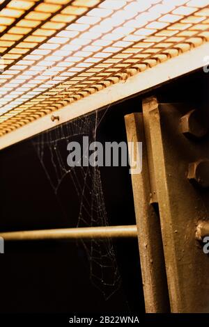 Auf das eingebaute Licht wartet ein Spinnennetz auf Metallgeländer Stockfoto