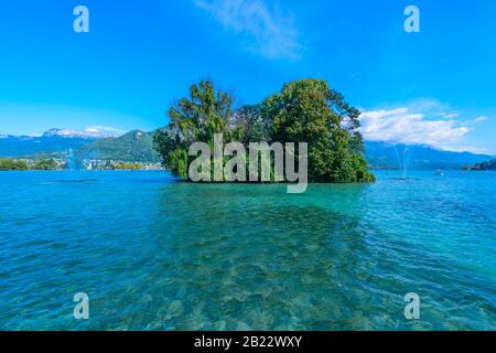 Eine kleine grüne Insel - Insel der Schwäne (L'île des Cygnes) am See von Annecy, einer der größten Seen in Frankreich, der als sauberster See Europas bekannt ist. Stockfoto