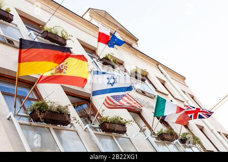 Mehrere schwenkende Flaggen an einer Gebäudefassade im Wind, Israel, Deutschland, Spanien, USA, Polen, Europäische Union, Italien, Frankreich, Großbritannien, viele Nationen Stockfoto