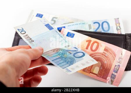 Handaufgabe von Geld in den Haufen europäischer Euro-Banknoten, kleine Rechnungen, die auf der schwarzen Geldbörse aufliegen, Einsparung von Geld, Rückzahlung, Beitrag, Effizienz Stockfoto