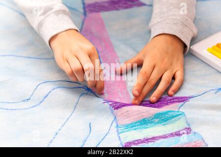 Einfache Kinderhände zeichnen mit Präzision auf einer riesigen Leinwand mit Ölpasten, Farbdetails, Nahaufnahme. Heimwerker, Kinder und Kunst, Kreativität und schaffen, Stockfoto