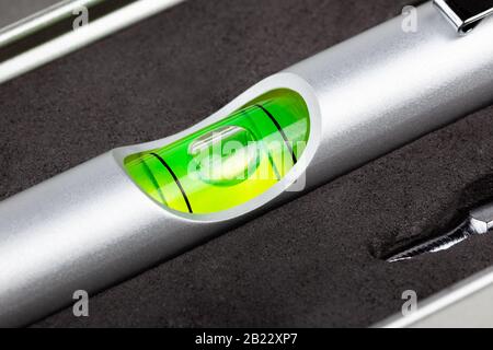 Kleine Mini-Wasserwaage, grüne Bullen Auge extrem Nahaufnahme Makro Silber Tasche Messwerkzeug, genaue Luftblase Nivellierung Instrument Detail Aufnahme Stockfoto