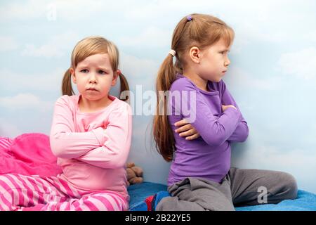 Zwei junge kleine Mädchen, Schwestern beleidigten sich gegenseitig, Geschwister streiten sich, kämpfen und nehmen das Vergehen zurück zum Rückenkonzept. Kinder, Kinder Familie Stockfoto