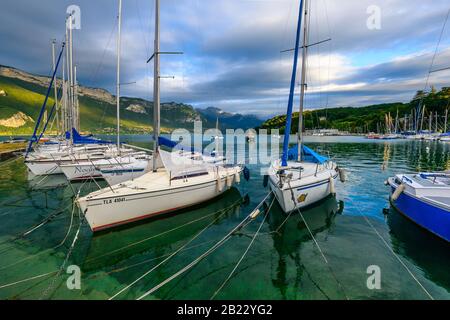 Segelboote, die auf dem See von Annecy, einem der größten Seen in Frankreich, der als sauberster See Europas bekannt ist, bei Sonnenuntergang festgemacht wurden. Stockfoto