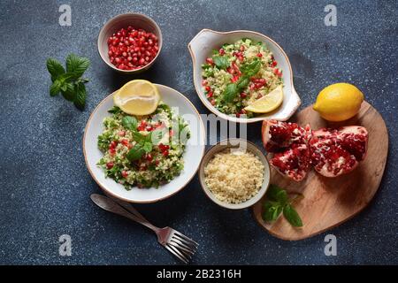 Gesunder Salat mit Couscous, frischer Minze, Gurke, Granatapfel, Zitrone und Olivenöl. Östliche Küche. Veganes Lebensmittelkonzept. Traditionelle israelische Küche Stockfoto