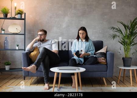 Junges Paar Sitzt auf dem Sofa. Die Frau Reißt Das Foto Auf. Familienkonflikt. Stockfoto