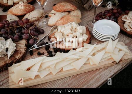 Käseplatte serviert mit Trauben, Marmelade, Feigen, Crackern und Nüssen auf Holzgrund. Draufsicht. Stockfoto