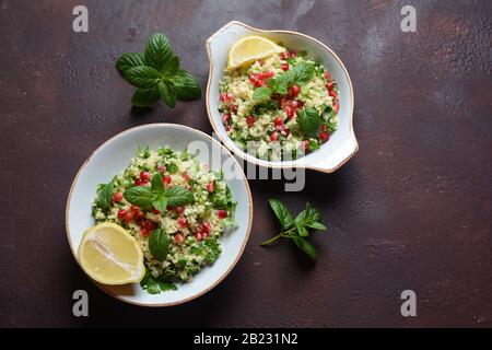 Gesunder Salat mit Couscous, frischer Minze, Gurke, Granatapfel, Zitrone und Olivenöl. Östliche Küche. Veganes Lebensmittelkonzept. Traditionelle israelische Küche Stockfoto