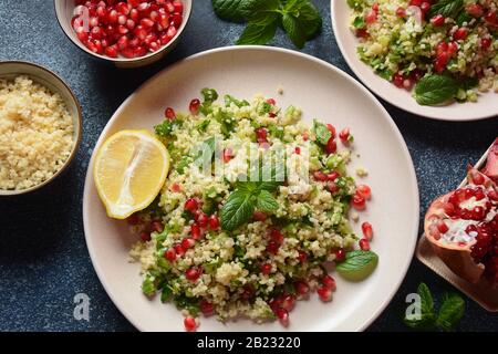 Gesunder Salat mit Couscous, frischer Minze, Gurke, Granatapfel, Zitrone und Olivenöl. Östliche Küche. Veganes Lebensmittelkonzept. Traditionelle israelische Küche Stockfoto