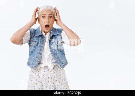 Panik, ängstlich und sprachlos, schockierte kaukasische Seniorin, die Sprachstare verlor, erschreckt und verängstigt, Kopf berühren, Kiefer fallen lassen und besorgt schnappen Stockfoto