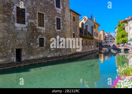 Der Fluss Thiou und die Seite des mittelalterlichen Le Palais de l'Ile von Quai de l'Ile, Annecy, Frankreich, an einem hellen Septembertag aus gesehen. Stockfoto