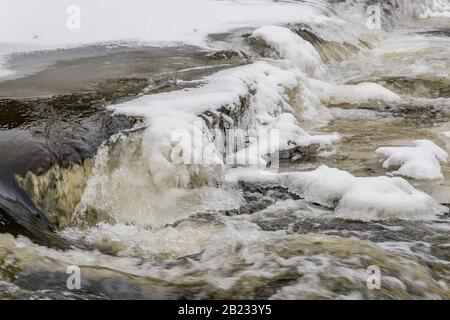 Eis und Schnee auf Kaskaden von altem zerbrochenem Wehr an einem Fluss, Stribro Stockfoto