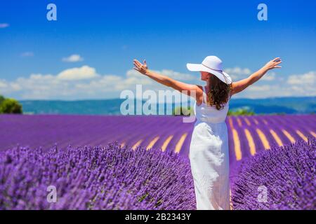 Provence, Frankreich. Ein Mädchen in weißem Kleid, das durch Lavendelfelder läuft. Stockfoto