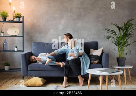 Junge Mutter Spielt mit Kindern auf der Couch. Glückliche Familie. Häuslicher Komfort. Stockfoto